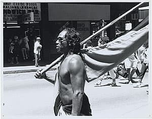 Michael RILEY | Dawson Drew [man carrying flag in street march], c. 1983