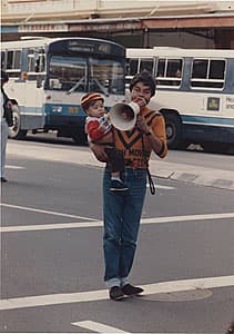 Michael RILEY | Graham Simpson, Todd Caroll (Man carrying baby, holding megaphone]